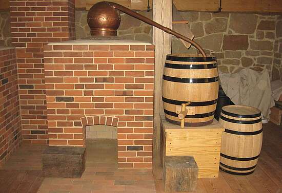 Brennblase mit Holzfeuerung, Kamin (hinten links) und Kühlwasserzufuhr vom Kühlwasserzufluss (hinten oben)